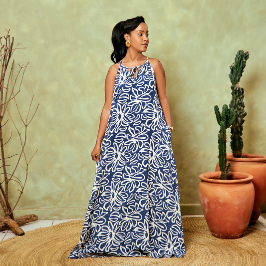 Woman wearing a blue and white patterned dress standing in front of potted plants.